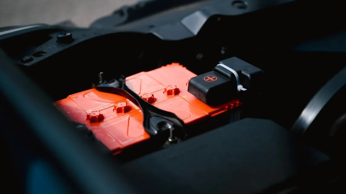 Orange car battery sitting in the engine bay of a vehicle