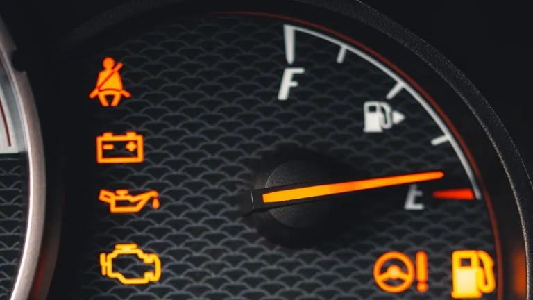 Car dashboard gauge cluster with the orange check engine warning light illuminated
