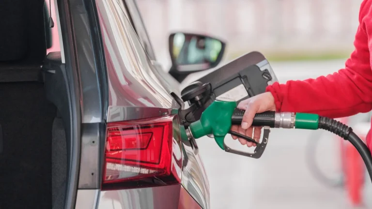 Close-up of a person refueling a car at a gas station pump