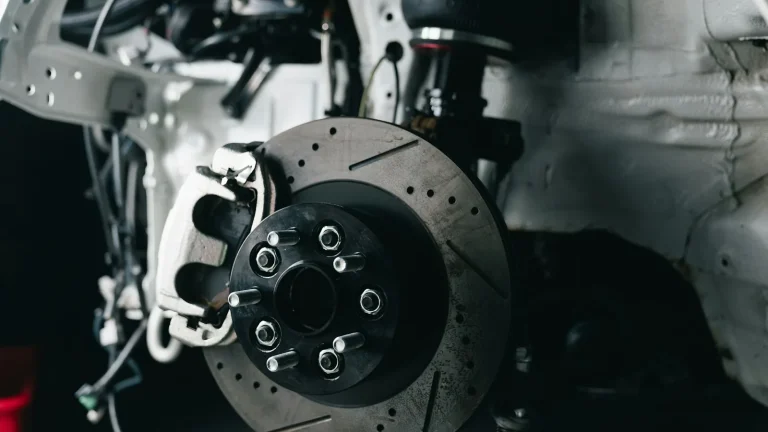 Front wheel hub with drilled brake disc and caliper on a car with the wheel removed