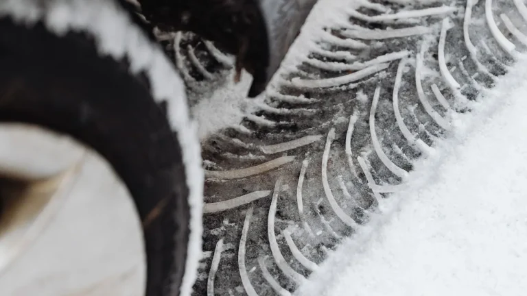 Close-up of a winter tire and its tread pattern pressed into fresh snow